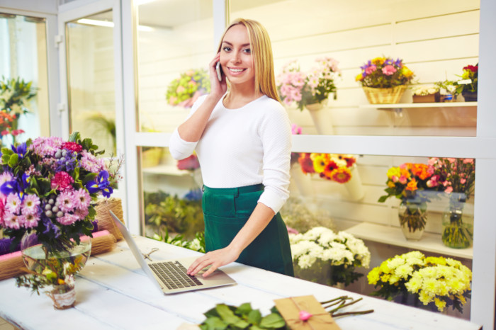 Propellerhead Hosting woman with phone and computer standing behind counter in a flower store